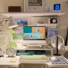 a desk with a computer, keyboard and headphones on it next to a lamp