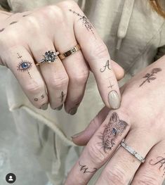 two people with matching tattoos on their fingers holding each other's hands and looking at the camera