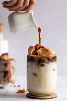 someone is pouring milk into a dessert in a jar