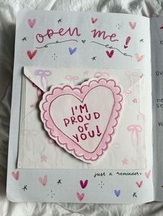 an open book with a pink heart and i'm proud you written on it