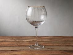 an empty wine glass sitting on top of a wooden table next to a gray wall