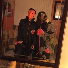 a man and woman are taking a selfie in front of a mirror with masks on