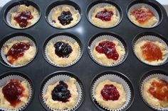 twelve cupcakes with jam in them sitting on a tray ready to be baked