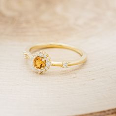 a close up of a gold ring with an orange stone in the middle and white diamonds around it