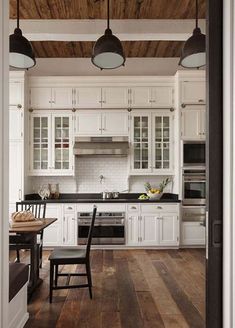 an open kitchen with white cabinets and wood flooring in the center, along with two black chairs