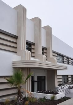 an art deco building with palm trees in front