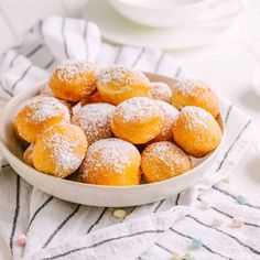 a bowl filled with powdered sugar covered donuts