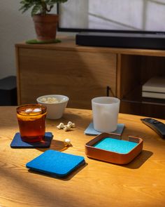 a wooden table topped with coasters next to a bowl of popcorn