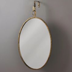 an oval mirror hanging on the wall next to a hook with a chain around it