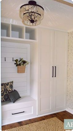 a room with some white cabinets and a chandelier hanging from it's ceiling