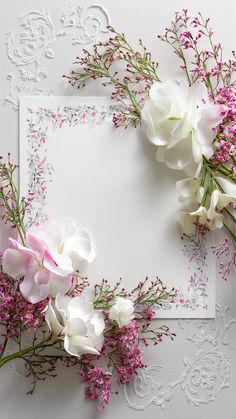 white and pink flowers are placed on top of an ornate paper with lace doily