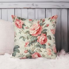 a pillow with pink flowers on it sitting on a white furnishing next to a wooden headboard