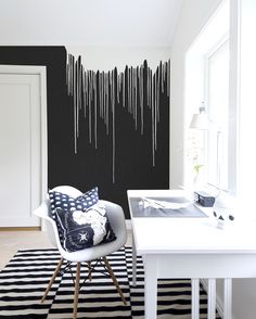 a black and white living room with an abstract wallpaper design on the wall, along with a striped rug