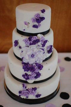 a three tiered cake with purple flowers on it