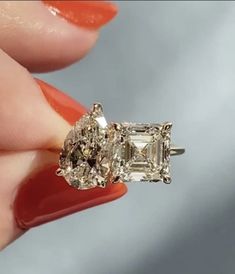 a woman's hand holding an engagement ring with three stone diamonds on it,