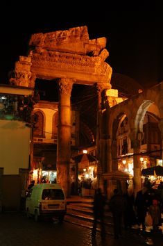 people are walking around an old building at night