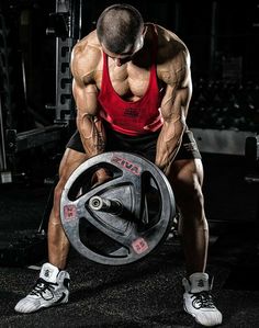 a man is squatting down with a barbell in front of him and holding a weight plate behind his back