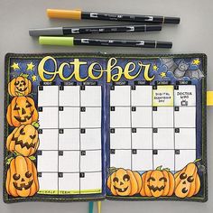 an open planner with pumpkins on it and two markers in front of the page