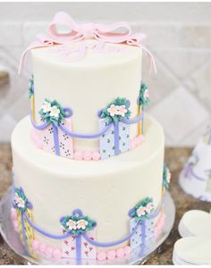 a three tiered cake with bows and presents on the top is decorated in pastel colors