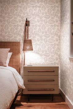 a bedroom with a bed, nightstand and wallpaper in the corner next to a window