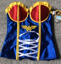 a blue and yellow wonder costume laying on the floor next to a card game box