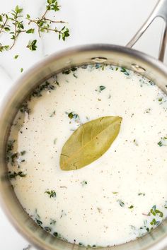 a green leaf is placed on top of the milk in a saucepan with spoons