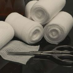 several white towels and some scissors on a black table with brown bottles in the background