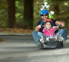 a man and girl are riding on roller skates in the park with helmets on