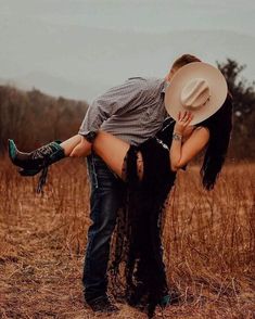 a man and woman kissing in the middle of a field