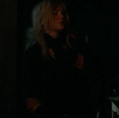 a woman with blonde hair standing in the dark