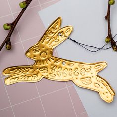 a gold bird ornament sitting on top of a piece of paper next to some branches