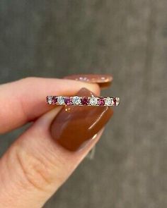 a woman's hand holding a diamond and ruby band