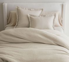 an unmade bed with white linens and pillows