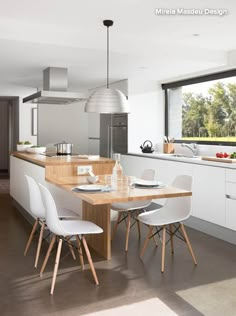 an image of a modern kitchen setting with white chairs and wood countertops, in the middle of a large open floor plan