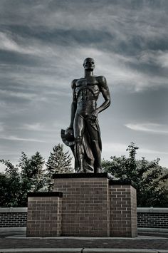 a statue of a man standing on top of a brick block wall