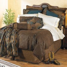 a bed covered in brown and white sheets with cowboy boots on the floor next to it