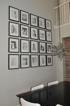 a dining room table with white chairs and pictures hanging on the wall above it in black and white