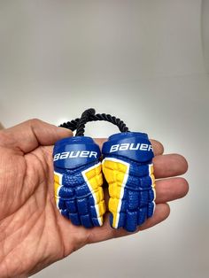 two blue and yellow gloves are held in the palm of a person's hand