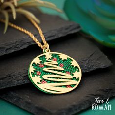 This Christmas Tree Pendant Necklace is a beautiful gift for anyone who is enchanted with the Christmas Holiday!  This Brass Holiday Christmas Tree Pendant features a Festive Christmas Tree design that has been carefully handmade and painted in our studio. Christmas Trees was a symbol of protection and renewal during the darkest winter in many ancient cultures. Today the Christmas Tree has become as a sign of everlasting life, peace, and rebirth. This brightly colored Pendant Necklace has an eye Christmas Holiday Green Jewelry, Green Christmas Holiday Jewelry, Festive Round Christmas Jewelry, Personalized Christmas Jewelry For Holidays, Personalized Christmas Holiday Jewelry, Personalized Jewelry For Holidays, Green Christmas Jewelry For Festive Occasion, Gold Necklace For Festive Christmas Occasion, Round Christmas Necklace As Gift