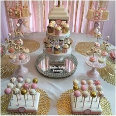 a table topped with lots of cakes and cupcakes next to pink balloons in the air