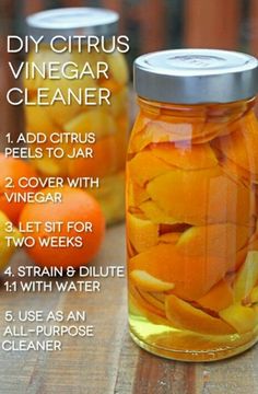 a jar filled with orange peels sitting on top of a wooden table next to other fruit