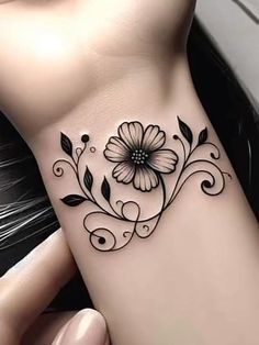 a black and white flower tattoo on the side of a woman's right arm