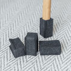 three pieces of black felt sitting next to each other on a white surface with a wooden stick sticking out of it