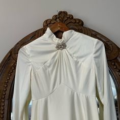 a white shirt hanging on a wooden hanger in front of a mirror with an ornate frame