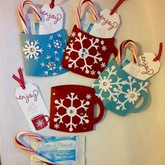 four christmas gift tags with candy canes and candies hanging from the handles on a white table