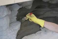 a man in yellow gloves is cleaning the inside of a rock cave with a sponge