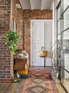 a room with a brick wall and wooden flooring next to a white door that has a large rug on top of it