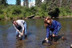 two people are standing in the water with buckets