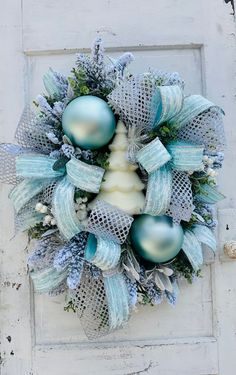 a wreath with blue and silver ornaments hanging on a white doorknobl that is decorated with mesh