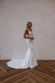 a woman in a white wedding dress standing on a wooden floor with her back to the camera